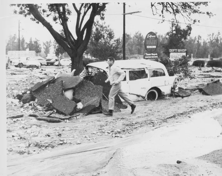 A man runs past a station wagon that was washed two blocks down Carnelian Avenue, along with part of the road surface. (Daily Report photo)