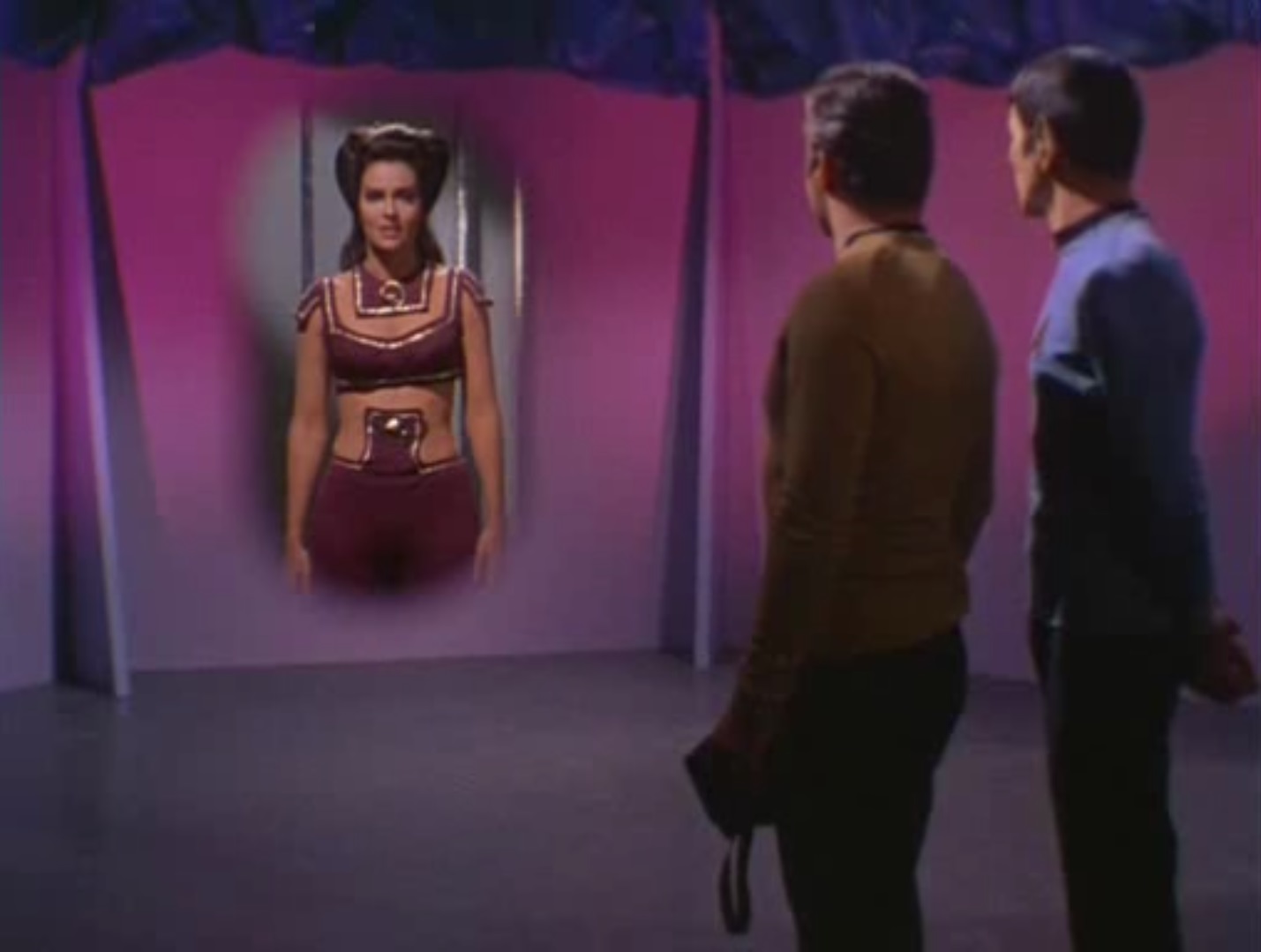 Losira appears holographically on a wall in front of Kirk and Spock after her computer is phasered