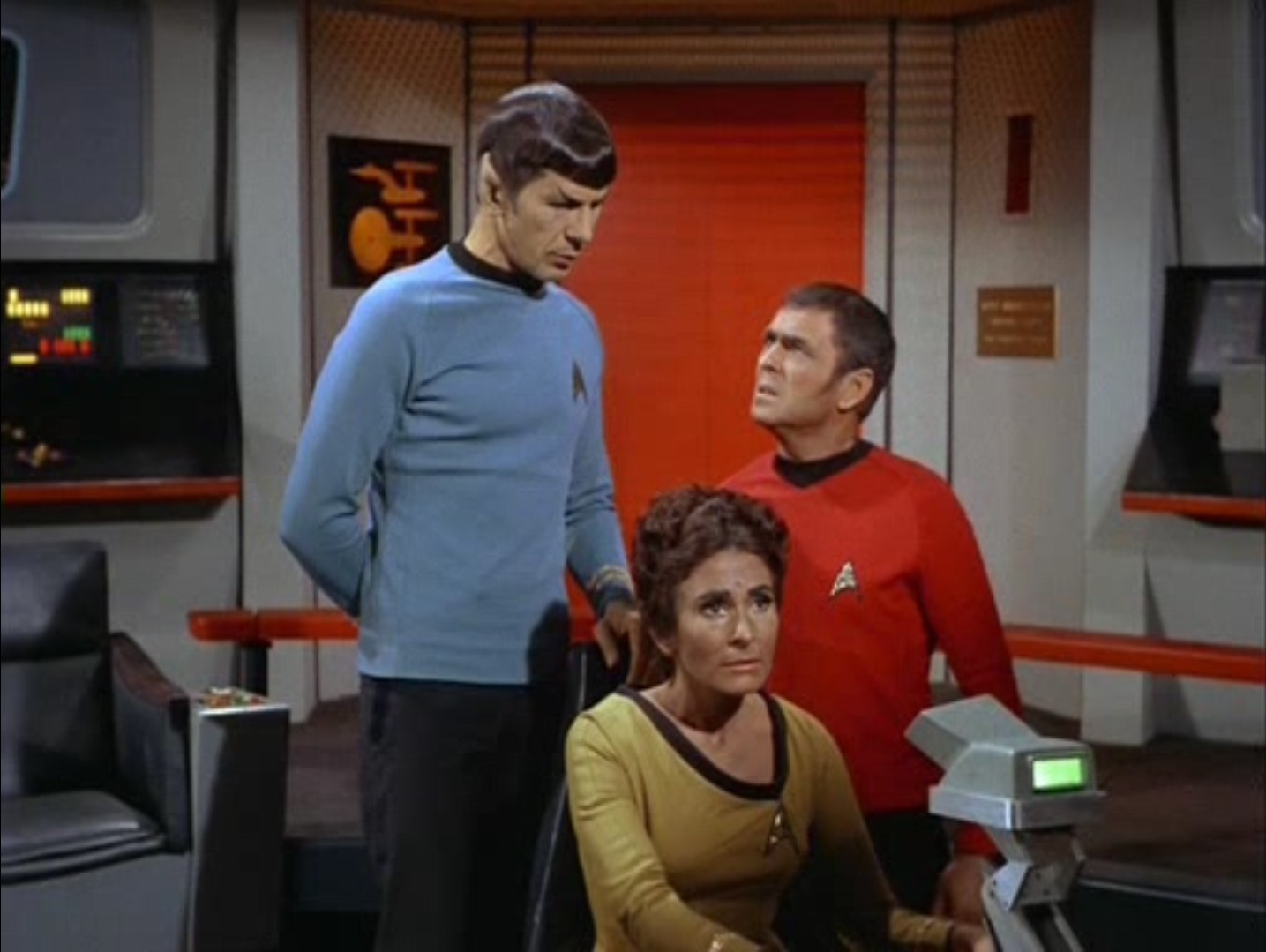 Spock standing behind Lt. Rahda, Scotty looking up at him, on the bridge