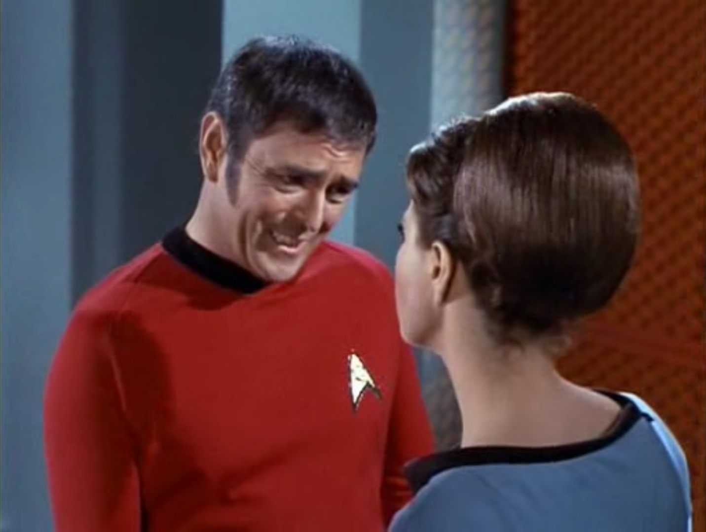 Image of a smiling Scotty looking down at, and trying to comfort, Mira, both in the extension to engineering first seen in the episode, Mirror, Mirror