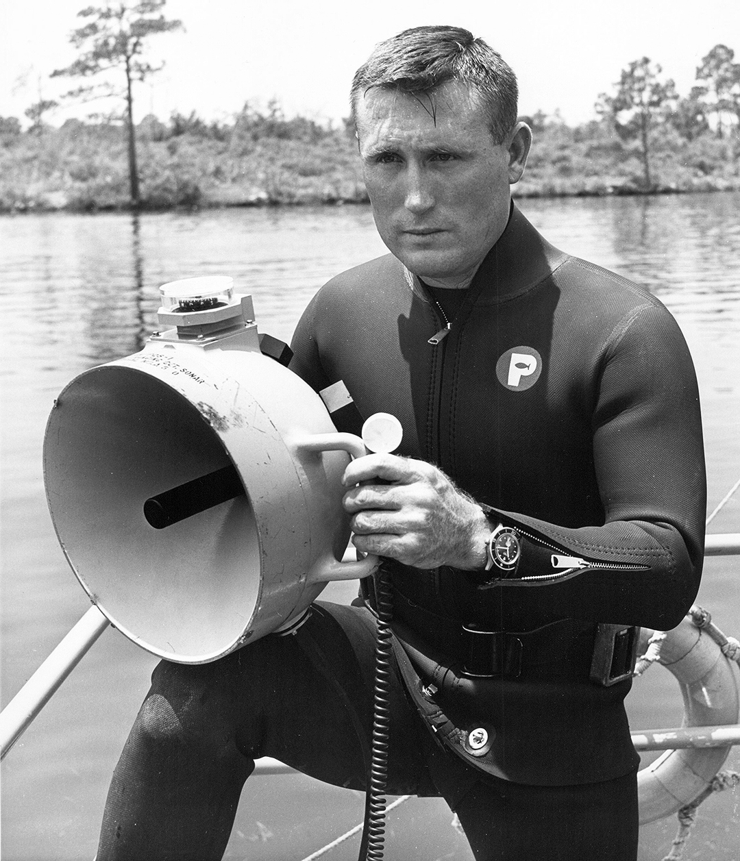 picture of a crewcut man in a diving suit behind a ship's lantern