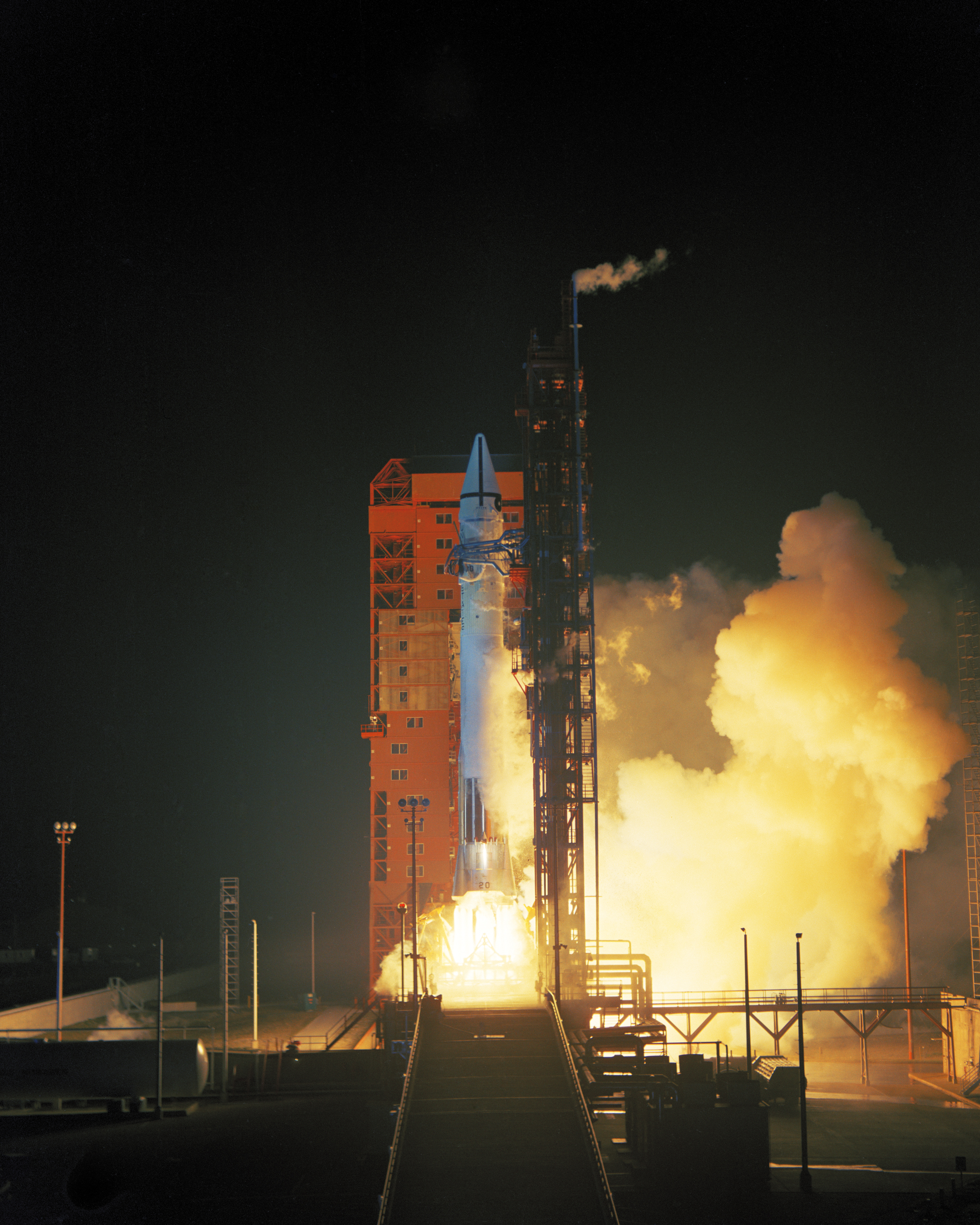 color photo of an Atlas Centaur rocket taking off from a red launch complex at night