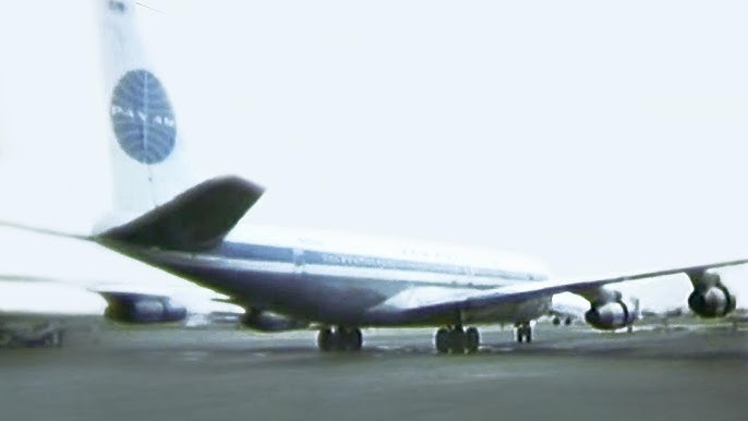 Photograph of a landed airplane seen from the rear right side. The logo on the airplane's tail says PAN-AM over a blue circle crisscrossed with white curved lines.