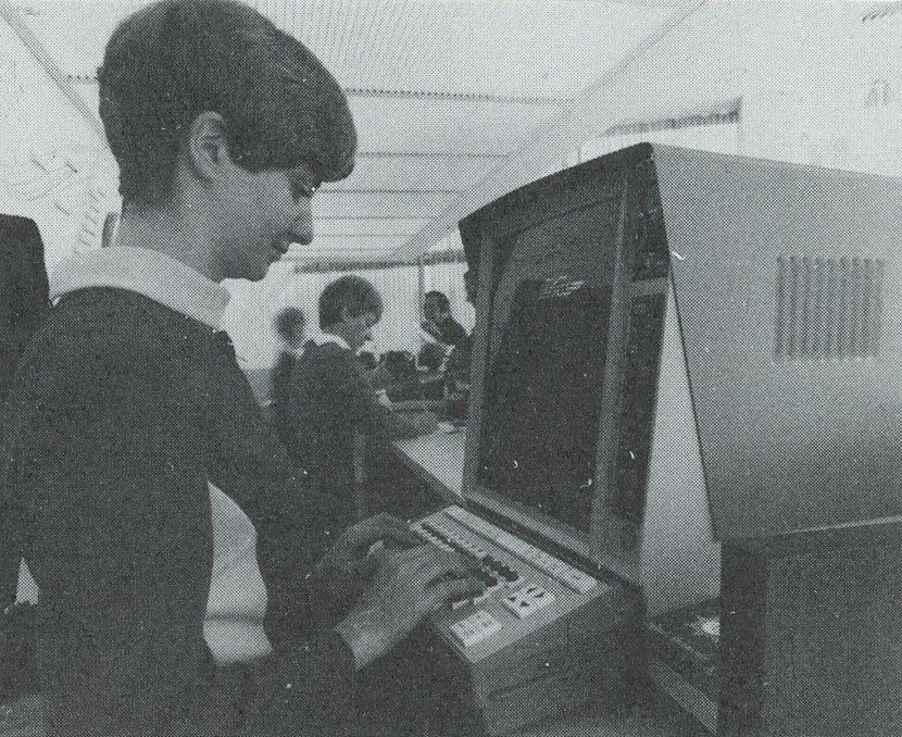 A short-haired brunette woman with a white collar types at a computer -