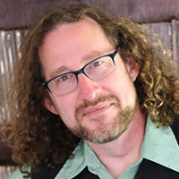 photo of a man with glasses and curly, long, brown hair, and a beard and mustache