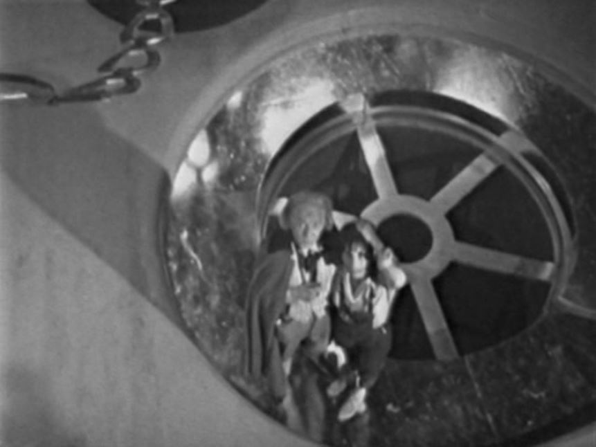 The Doctor and Susan stand at the rim of a gigantic plughole.