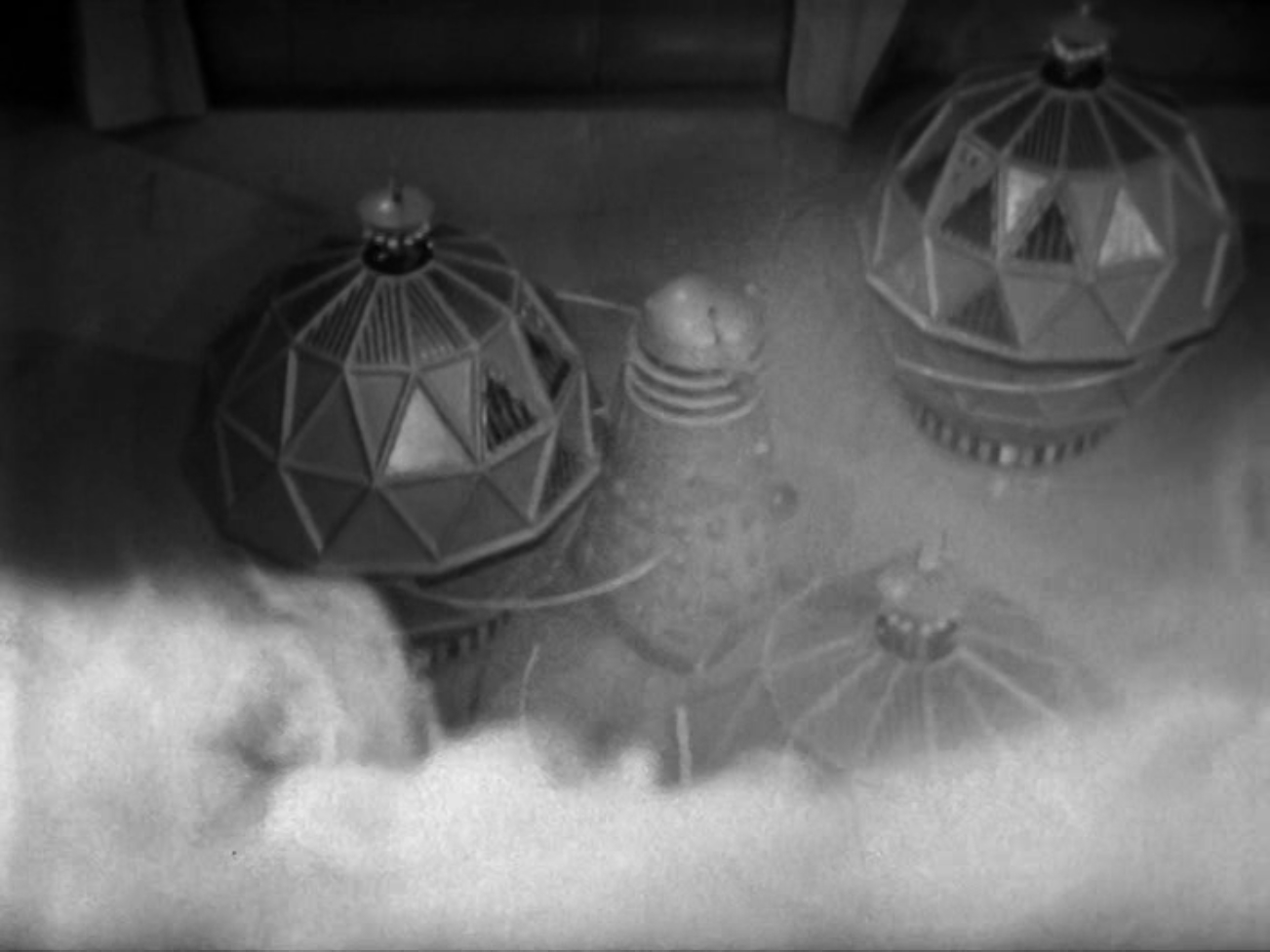 Image description: Three Mechanoids surround a Dalek.