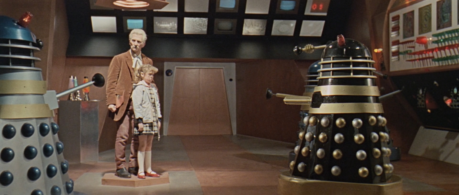 Image description: On the left Dr. Who and Susan stand together under a beam of light. On the right is a black Dalek.