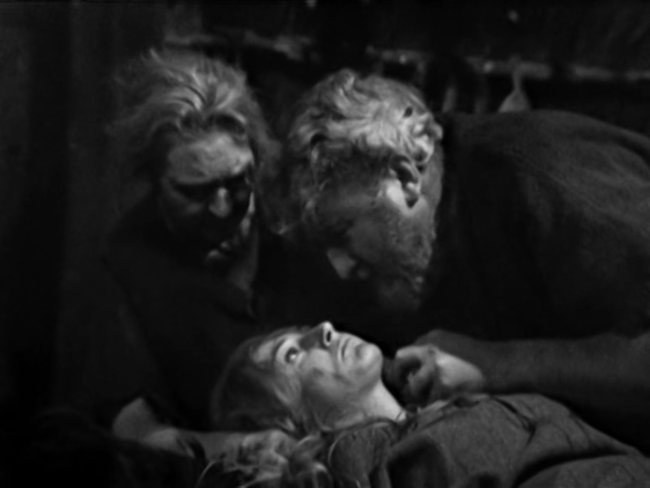 Image description: Edith's husband and another woman look down on Edith as she lies down. She appears traumatised.