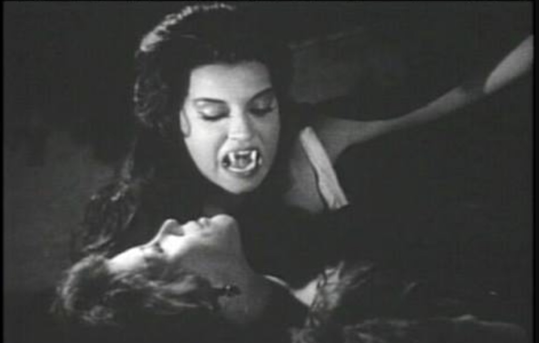 Vampire woman leans down to drink Diana's blood.