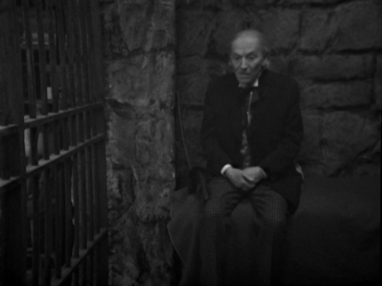 Image: The Doctor sits in a jail cell.