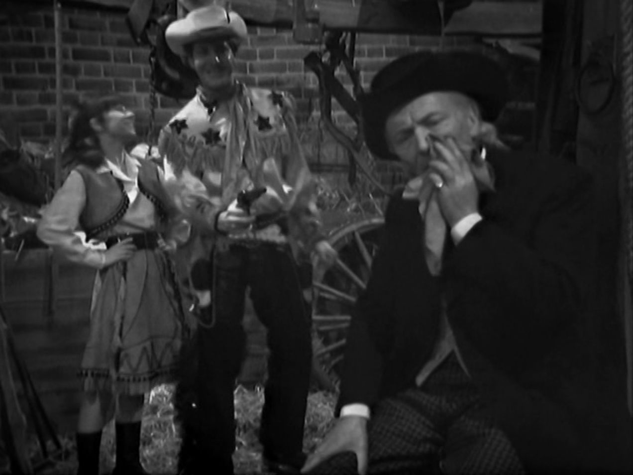 Image: Stephen and Dodo in bad cowboy costumes, with the Doctor clutching his jaw in the foreground.