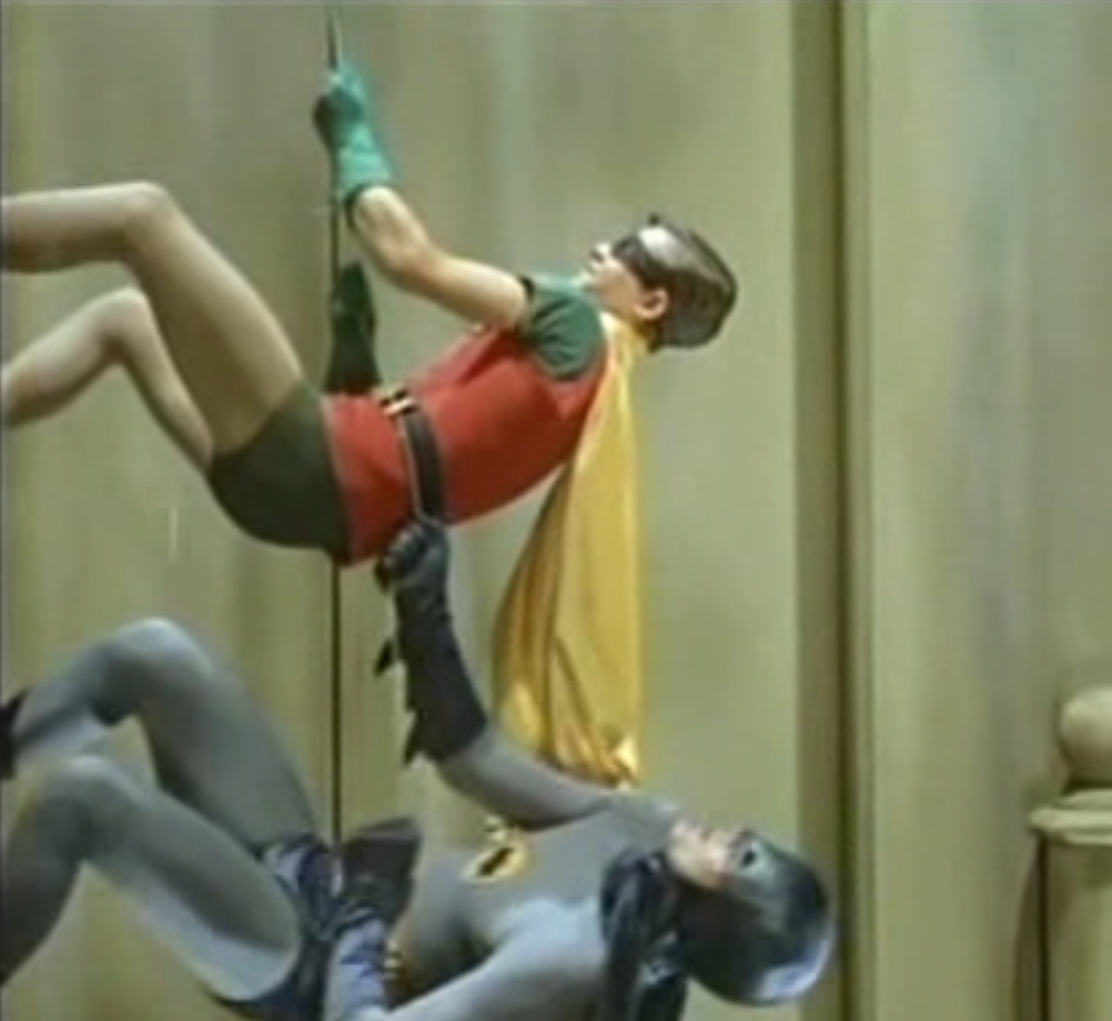 Batman and Robin climbing a wall using a batarang cord