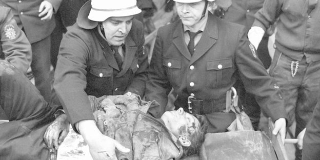 Police officers carry off the wounded assassin Josef Bachmann