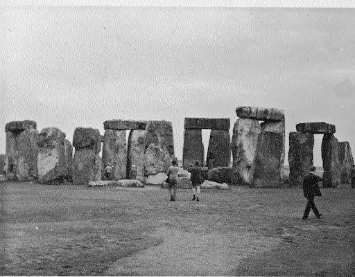 Black and white photo of the large, rectangular bloks that comprise Stonehenge with visitors in front of them