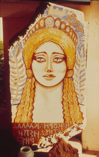 Picture of the maiden goddess Kore, with golden hair and wheat in the background behind her.