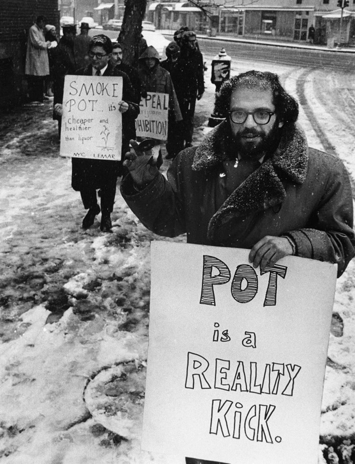 Black and white photo of a protest to legalise marijuana, at the front is Allen Ginsberg holding a sign that says "Pot is a reality kick"