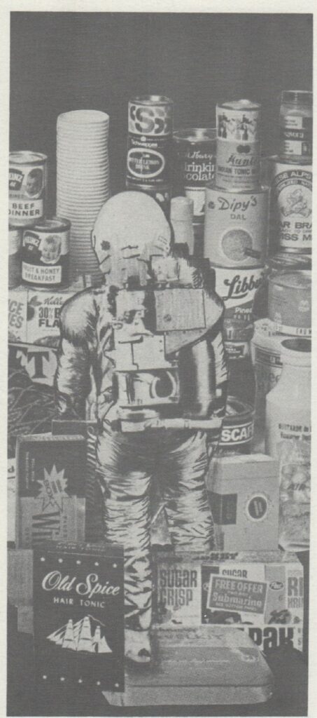 IMAGE: An photo of a man in an astronaut’s suit surrounded by supermarket products.