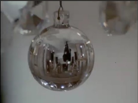 Still frame from the TV series Night Gallery. It shows a close-up of a hanging glass ornament. In it we can see an upside-down reflection of a man walking down a hallway.