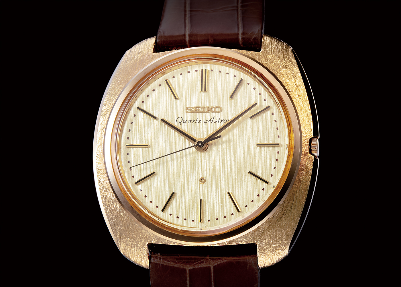 photograph of a gold watch with a brown leather strap. In the center of the face, letters spell out Seiko-Astro