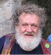 Photograph of an older white man with gray curly hair and a thick white beard.