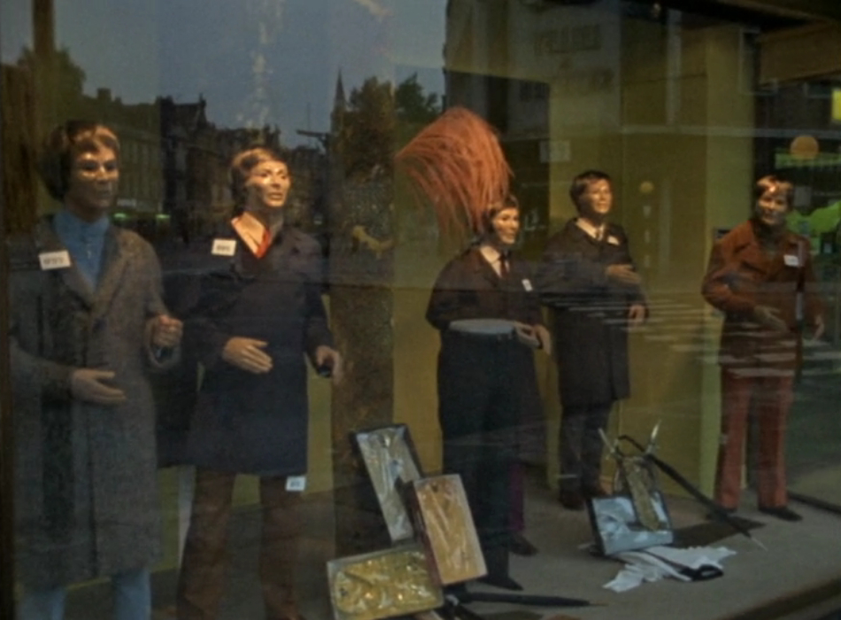 A shop window with 5 dressed dummies behind the glass.