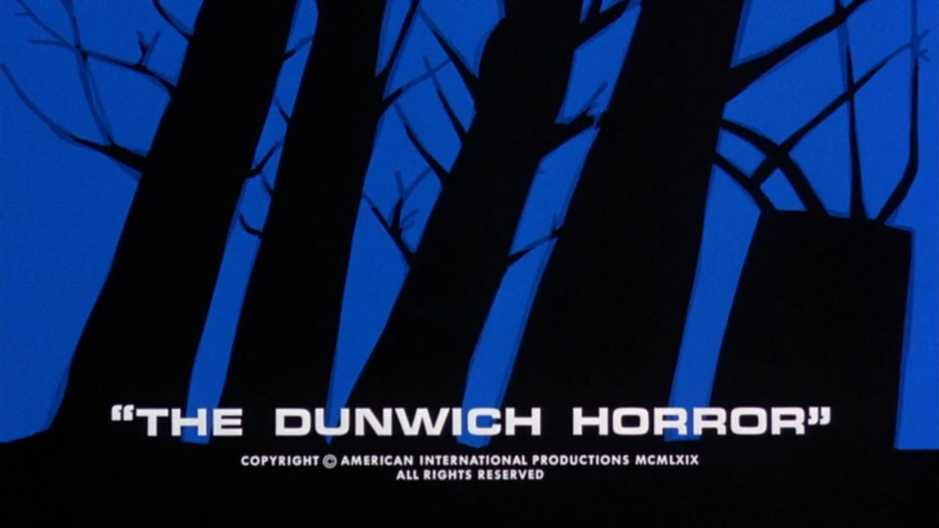 The title card from 'The Dunwich Horror.' The title is written in white capitals, and includes the quotation marks. behind the title are abstract silhouettes of trees with short, spiky branches stand against a dark blue background.