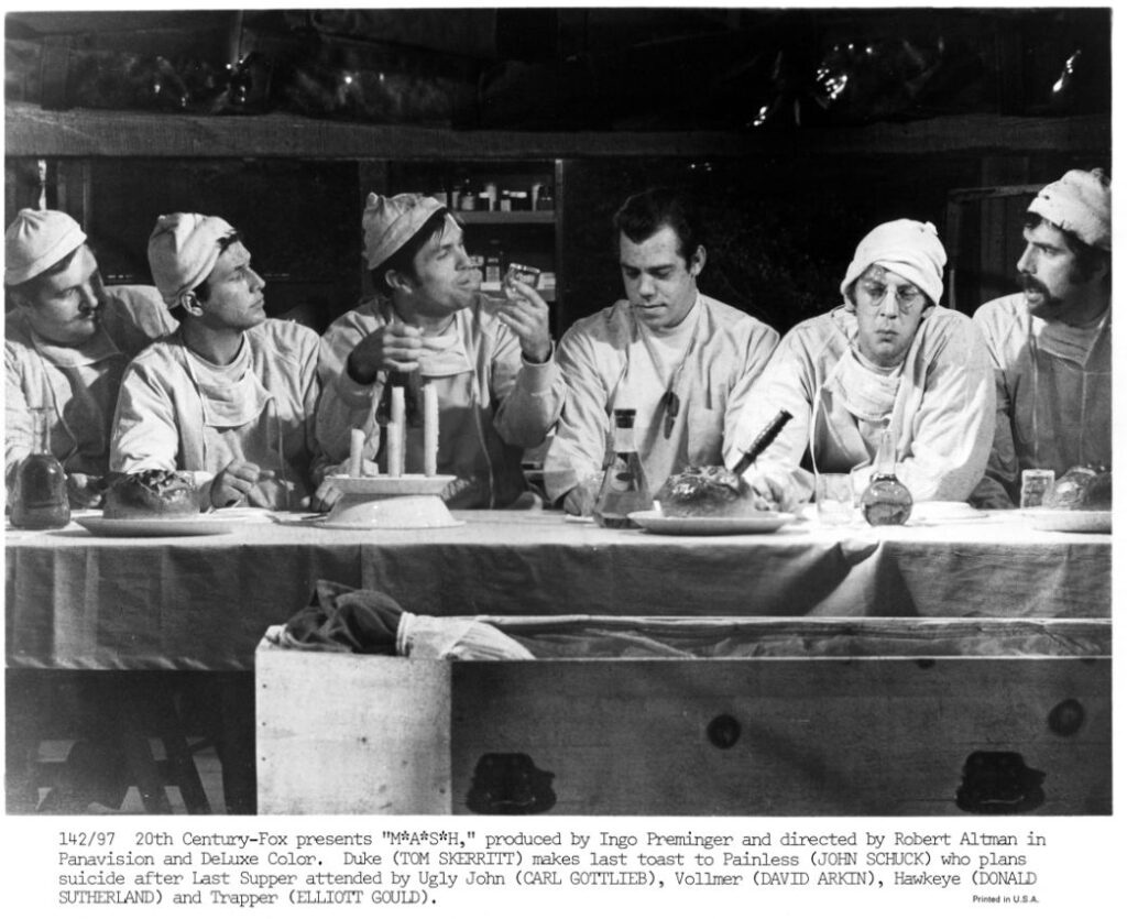 six white men sitting at a table, arranged in a way that echoes the Last Supper