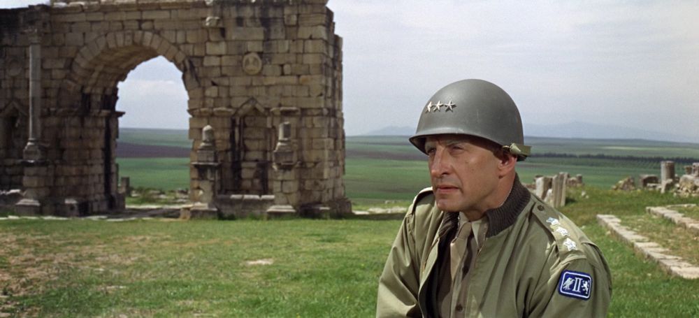 Color picture of Patton, standing in the deep grass within Italian ruins