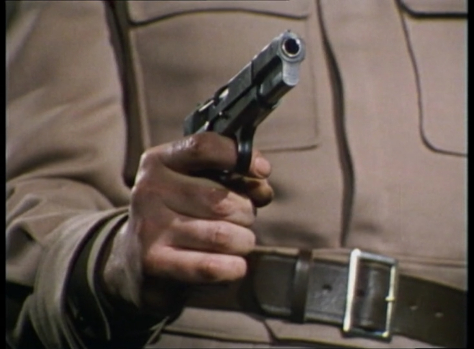 A closeup of a pistol in the Brigadier's hand.