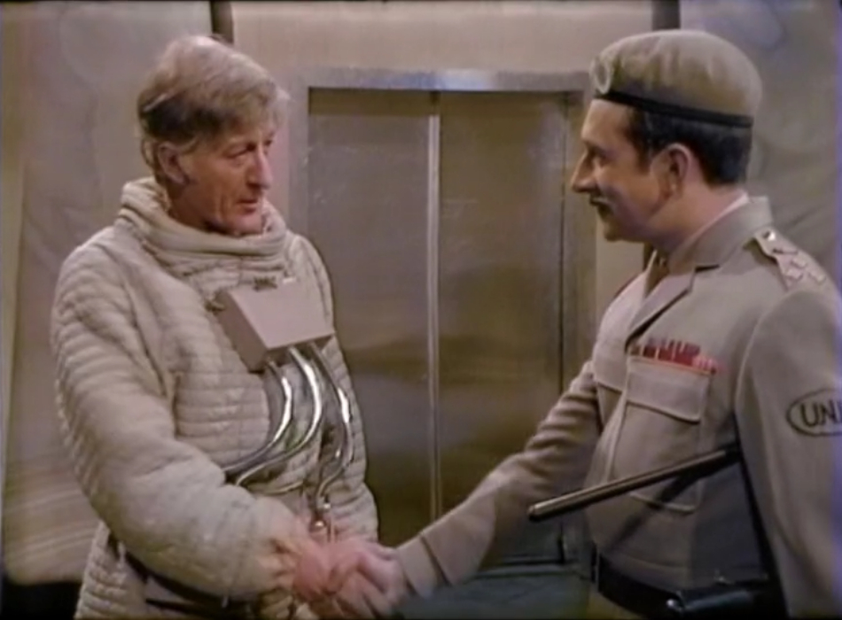The Doctor (wearing a spacesuit) and the Brigadier shaking hands.