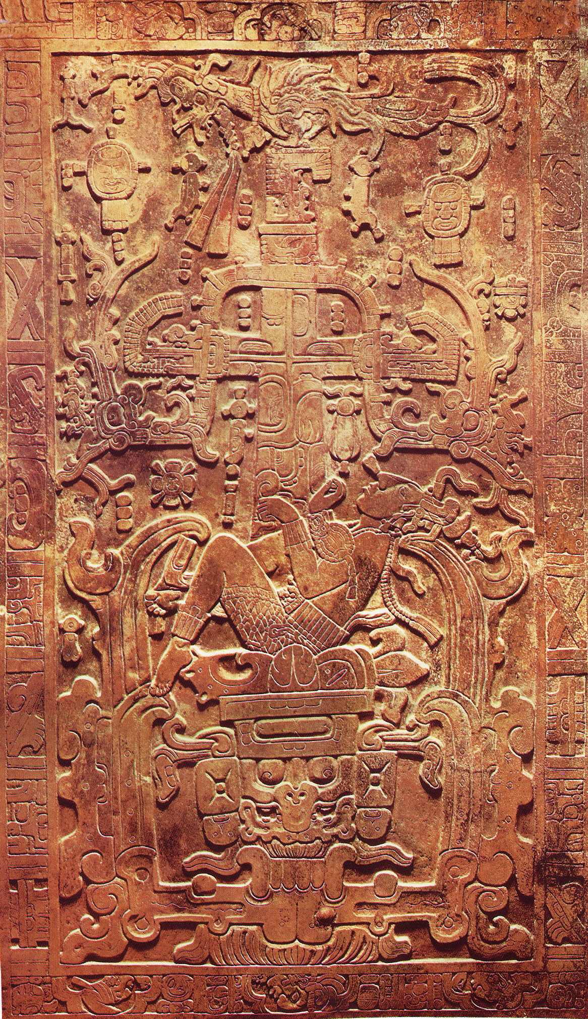 Photograph of an a person reclining on a couch, intricately carved illustration in relief cut in a smooth slab of mottled brown stone