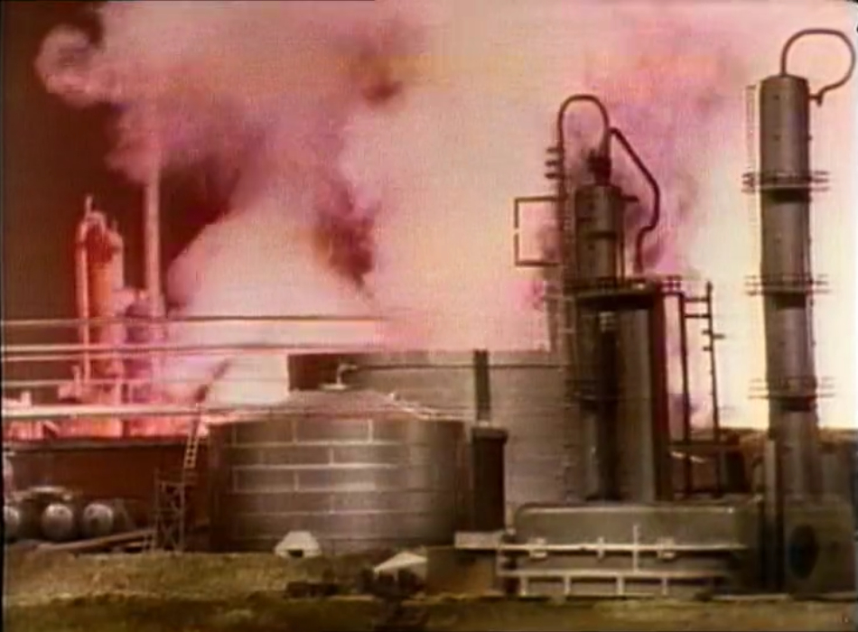 The drilling facility with smoke billowing out and an eerie red glow.