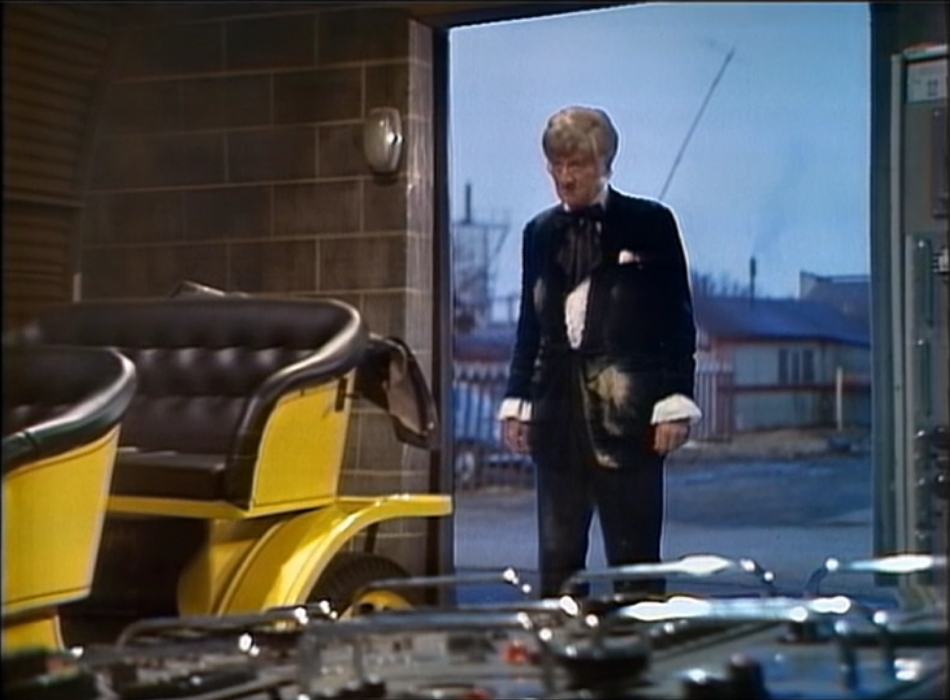 The Doctor standing in the door of his workshop with his clothes very dirty.