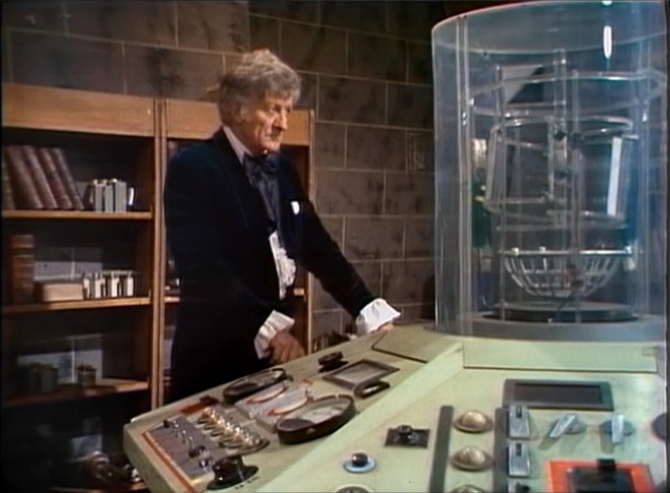 The Doctor standing at the TARDIS console with a peeved expression.