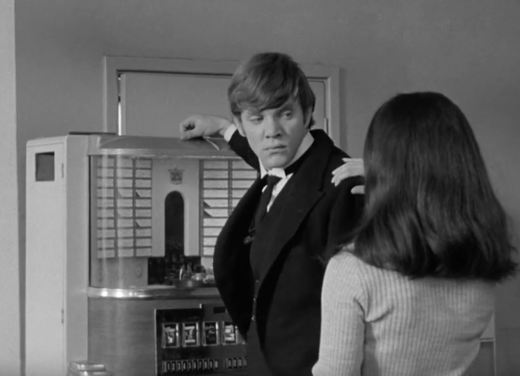 Malcolm McDowell and Christine Noonan in black and white at a jukebox.
