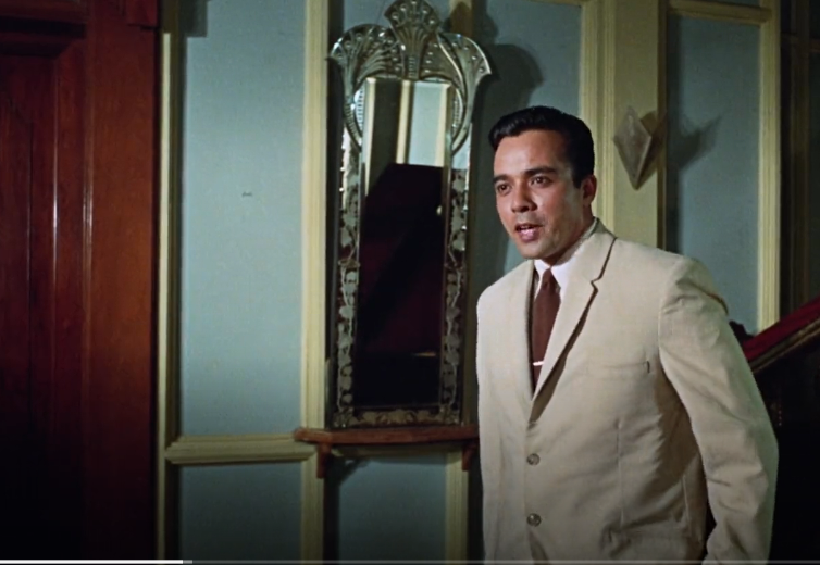 The relevant fellow, a perfectly coiffed young man in an cream-colored suit, standing in a lovely Art Deco hallway.