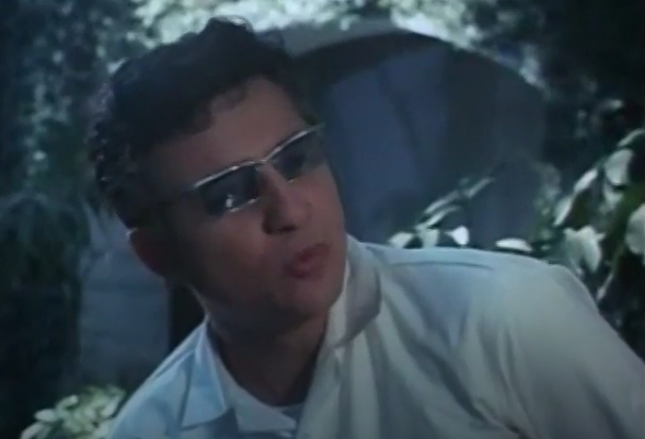 A color image of the Mad Doctor, pursing his lips at the camera. He is wearing a loose white shirt and a large, futuristic pair of sunglasses.