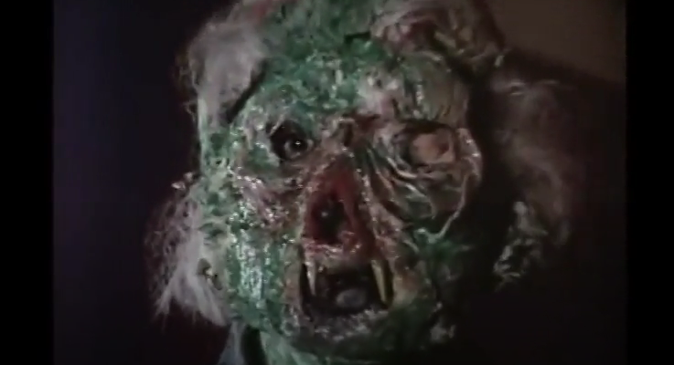 Color image of the monster in question. It is a flattish green mask with blonde hair and two protruding fangs.