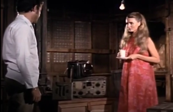 Color image of the reporter and the hero. She is wearing a red-and-coral floral dress and carrying a white cup. He is in a white shirt with dark slacks.