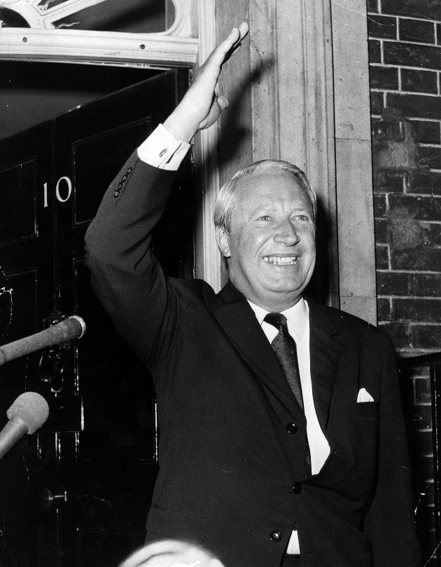 Black & White Photo of Prime Minister Edward Heath outside the door of 10 Downing Street, waving to the crowd Two microphones can be seen off the left hand side of the picture